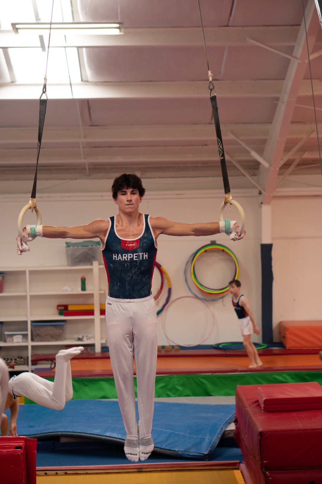 A boy on the Harpeth Gymnastics Boys Team practices on the rings.