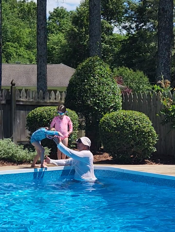 Coach Scott helps a swimmer perfect her diving form at the edge of the pool.