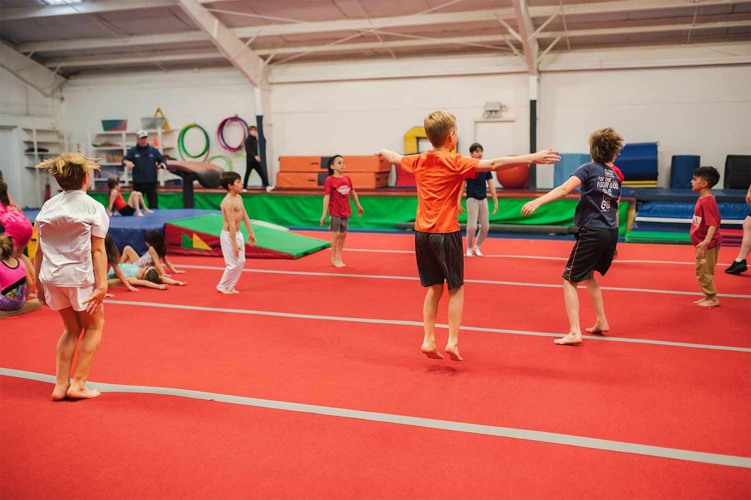 The boys recreational and boys team gymnastics members warm up for their classes together on the mat.